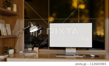 A contemporary office with a computer mockup on a wooden desk against the window with a night view. 112683965