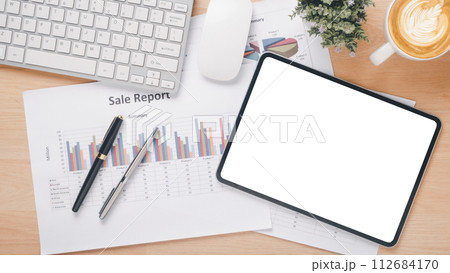 Workspace with sales report, digital tablet, keyboard, and cup of coffee on wooden desk. Workspace with sales report, digital tablet, keyboard, and cup of coffee on wooden desk. 112684170