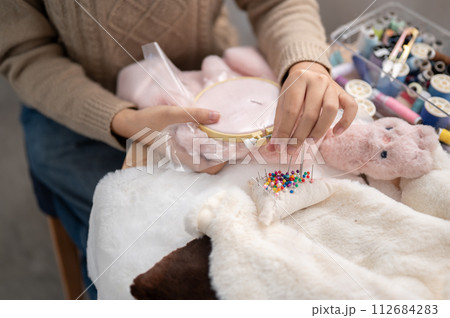 A close-up image of a woman pinning a pin on a pin cushion, stitching cloth, crafting handmade items. A close-up image of a woman pinning a pin on a pin cushion, stitching cloth, crafting handmade items. 112684283