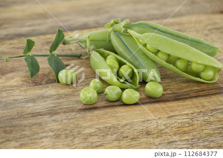 Group of fresh green peas with leaves on wooden surface 112684377