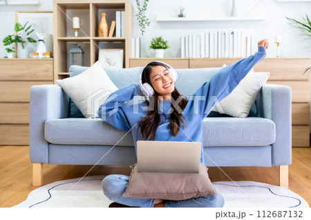 Young asian woman in good spirits working on laptop at home while sitting on the floor 112687132