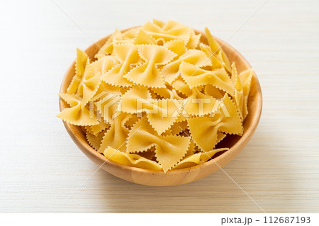 Dry uncooked farfalle pasta in bowl 112687193