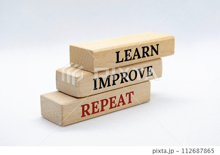 Learn, Improve and Repeat text on wooden blocks with white cover background. Improvement and development concept 112687865
