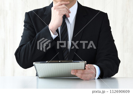 資料を見て考えるスーツを着た男性 資料を見て考えるスーツを着た男性 112690609