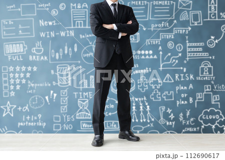 手書きのビジネスコンセプトの背景の前で考えるビジネスマン 112690617