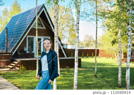 Portrait of cheerful woman in front of a-frame cabin Portrait of cheerful woman in front of a-frame cabin 112690914