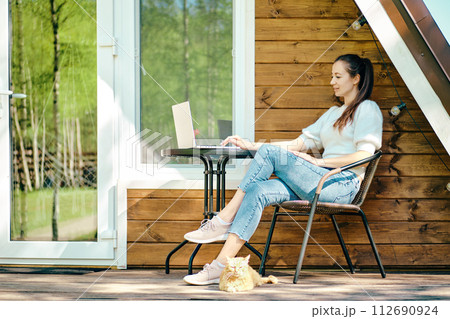 Relaxed woman sitting with laptop on terrace in a sunny day 112690924