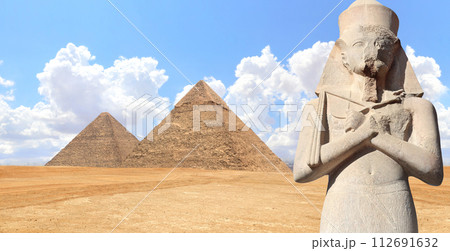 Horizontal banner with Stone pharaoh statue and famous Great Pyramids of Chephren and Cheops, Cairo, Egypt. Two Great Pyramids and ancient Ramses II statue, Giza pyramid complex (Giza Necropolis) 112691632