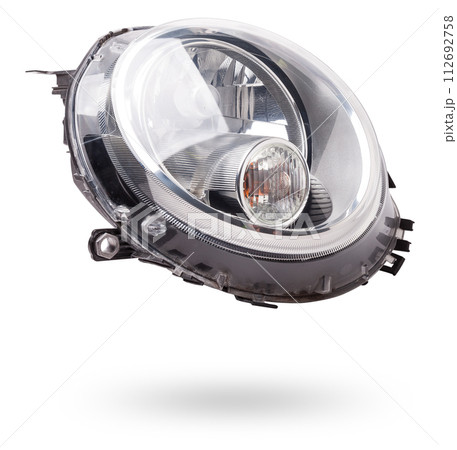 Stylish xenon headlight of a German car - optical equipment with a lamp inside on a white isolated background. Spare part for auto repair in a car workshop. Stylish xenon headlight of a German car - optical equipment with a lamp inside on a white isolated background. Spare part for auto repair in a car workshop. 112692758
