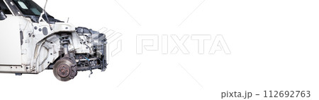 The front part of the car after an accident in a car repair service with a disassembled hood and metal grille and various parts in the garage box. 112692763