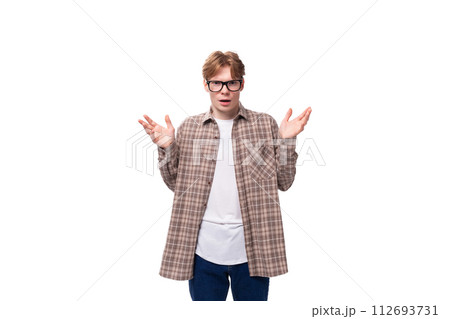young european man with red short hair and glasses shrugs his shoulders in surprise young european man with red short hair and glasses shrugs his shoulders in surprise 112693731