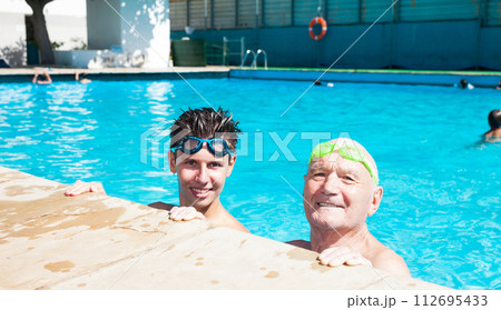 Grandfather and grandson communicate in swimming pool Grandfather and grandson communicate in swimming pool 112695433