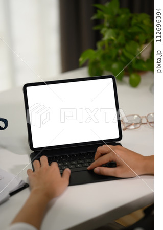 Closeup young businesswoman typing on keyboard, working with digital tablet at desk Closeup young businesswoman typing on keyboard, working with digital tablet at desk 112696394