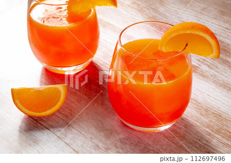 Orange drinks on a wooden background, fresh pressed juice with fruit slices Orange drinks on a wooden background, fresh pressed juice with fruit slices 112697496