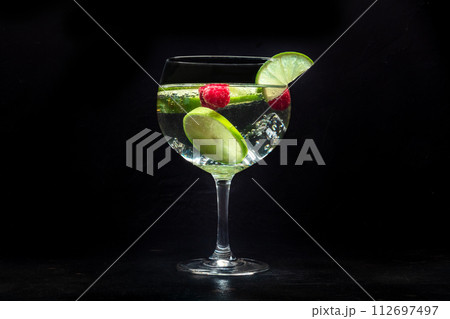 Fancy cocktail with fresh fruit. Gin and tonic drink with ice at a party Fancy cocktail with fresh fruit. Gin and tonic drink with ice at a party 112697497