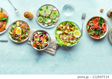 Fresh salads, overhead flat lay shot of an assortment. Variety of plates 112697514