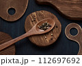Heap of black pepper, peppercorns in wooden spoon on rustic background. 112697692