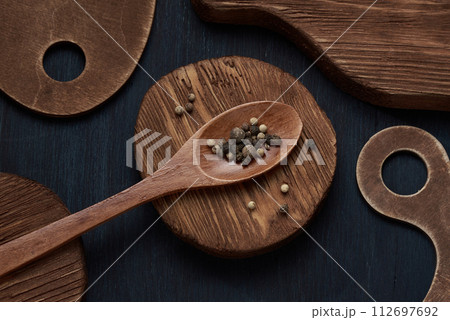 Heap of black pepper, peppercorns in wooden spoon on rustic background. 112697692