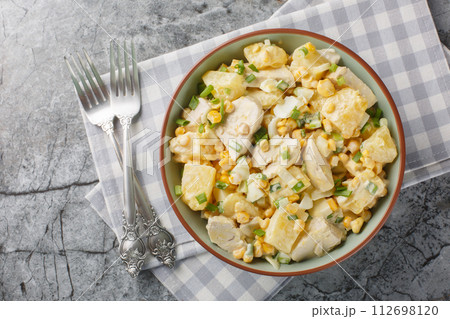 Homemade chicken breast pineapple salad with corn, cheese, eggs and onions close-up in a plate. Horizontal top view 112698120