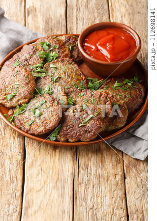 Beef liver cutlets served with tomato sauce close-up in a plate. Vertical 112698141