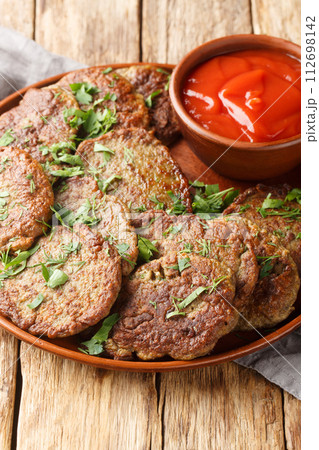 Delicious beef liver patties served with tomato sauce close-up in a plate. Vertical 112698142