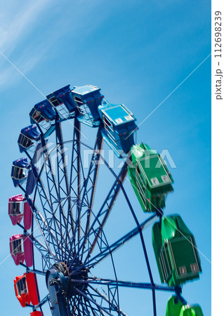Colorful ride in motion in amusement park on sky background. Colorful ride in motion in amusement park on sky background. 112698239