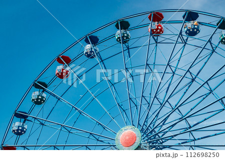 Colorful ride ferris wheel in motion in amusement park on sky background. Colorful ride ferris wheel in motion in amusement park on sky background. 112698250