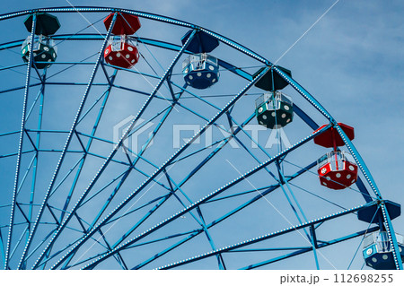 Colorful ride ferris wheel in motion in amusement park on sky background. 112698255