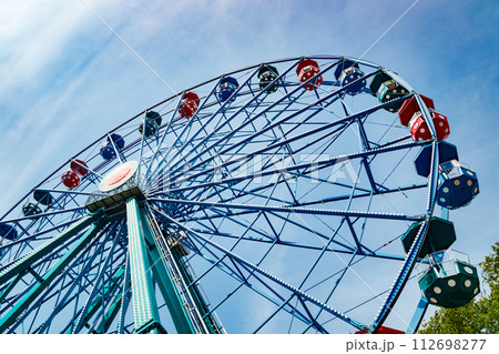 Colorful ride ferris wheel in motion in amusement park on sky background. 112698277
