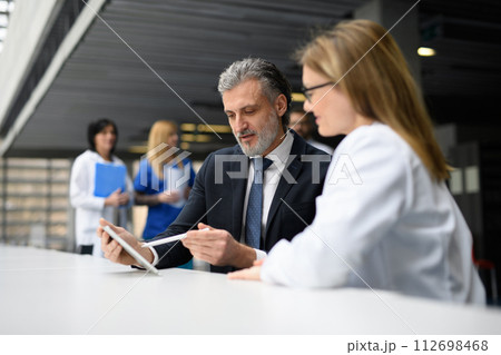 Doctor talking to pharmaceutical sales representative, shaking hands. Hospital manager talking with female doctor. 112698468