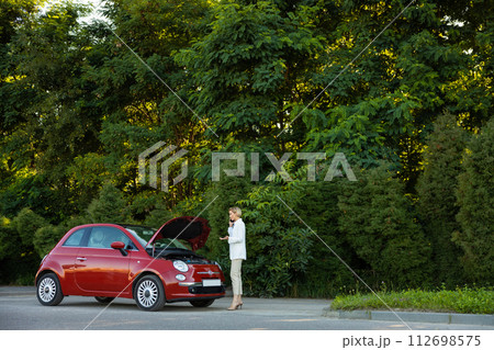 Young woman using mobile phone for calling to service for repairing her car Young woman using mobile phone for calling to service for repairing her car 112698575