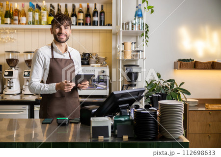 Bearded man bartender standing with digital tablet at coffee shop counter 112698633