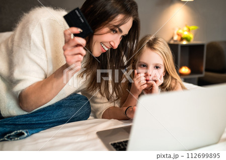 Woman and little daughter with laptop and credit card making online reservation of hotel room Woman and little daughter with laptop and credit card making online reservation of hotel room 112699895