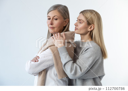 Blonde young woman hugging her mom and looking peaceful Blonde young woman hugging her mom and looking peaceful 112700786