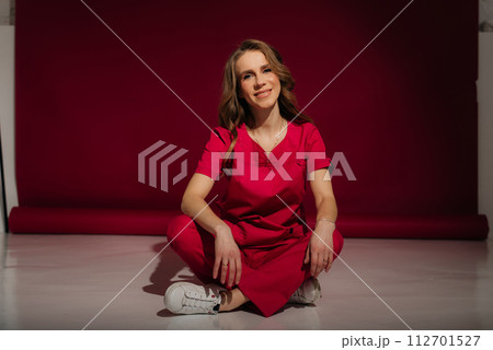 Medical nurse woman wearing red surgery suit, on red background. 112701527