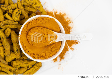 Turmeric powder, spices and dried root on white background. Top view, copy space for text. Turmeric powder, spices and dried root on white background. Top view, copy space for text. 112702300