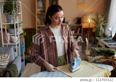 High angle portrait of young woman ironing clothes on laundry day and taking care of house chores copy space High angle portrait of young woman ironing clothes on laundry day and taking care of house chores copy space 112703522