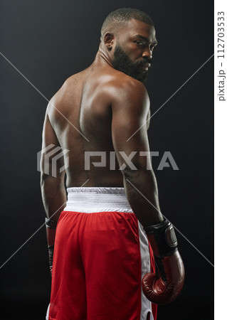 Vertical back view of muscular African American boxer posing shirtless and wearing boxing gloves 112703533