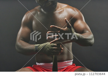 Dramatic cropped shot of fighter wrapping hands in bandages against smokey black background 112703644