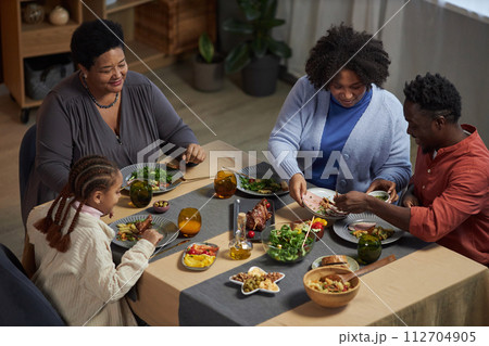 High angle portrait of three generation family enjoying dinner together sitting at table at home and sharing food 112704905