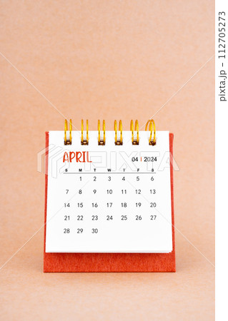 April 2024 white desk calendar on brown background. April 2024 white desk calendar on brown background. 112705273