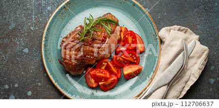 Delicious roasted duck breast fillet with golden crispy skin, with pepper and rosemary, top view on ceramic blue plate served with cherry tomatoes salad, rustic concrete rustic background Delicious roasted duck breast fillet with golden crispy skin, with pepper and rosemary, top view on ceramic blue plate served with cherry tomatoes salad, rustic concrete rustic background 112706637