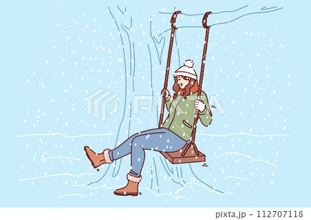 Woman swings on swing in winter park, rejoicing at falling snow and approach christmas or new year Woman swings on swing in winter park, rejoicing at falling snow and approach christmas or new year 112707118