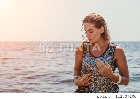 Woman summer travel sea. Happy tourist enjoy taking picture outdoors for memories. Woman traveler posing on the beach at sea surrounded by volcanic mountains, sharing travel adventure journey 112707186