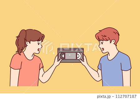 Surprised children are looking at film video cassette with movie recorded for VHS player Surprised children are looking at film video cassette with movie recorded for VHS player 112707187
