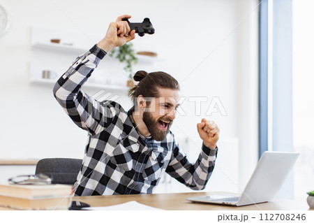 Attractive guy using joystick during leisure time at kitchen. 112708246