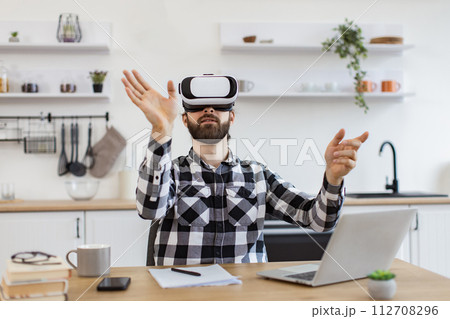 Caucasian worker testing VR headset while sitting at wooden table. 112708296