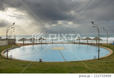round area for roller skating and dancing against the backdrop of the sea and thunderclouds 112710409