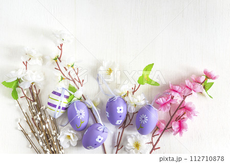Happy easter holidays concept; Artificial twigs with white and pink apple blossom and easter eggs on a white paint wooden background; copy space 112710878