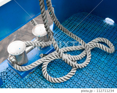 Coiled rope on a blue sailing boat deck. Sailing equipment aboard ship. Shipping concept Coiled rope on a blue sailing boat deck. Sailing equipment aboard ship. Shipping concept 112711234